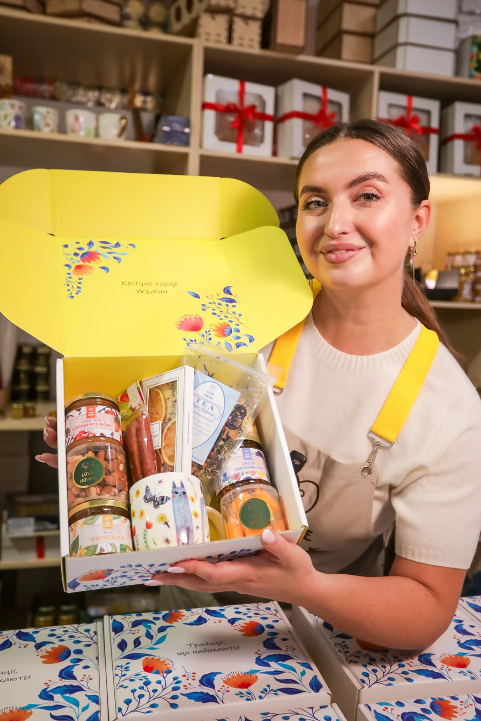 Відкритий жовтий бокс LOVE HONEY з медом, горіхами, чаєм і чашкою в руках менеджерки